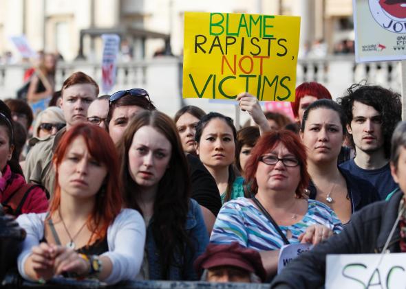 Women during an anti-rape protest display a sign saying 'blame rapists not victims'