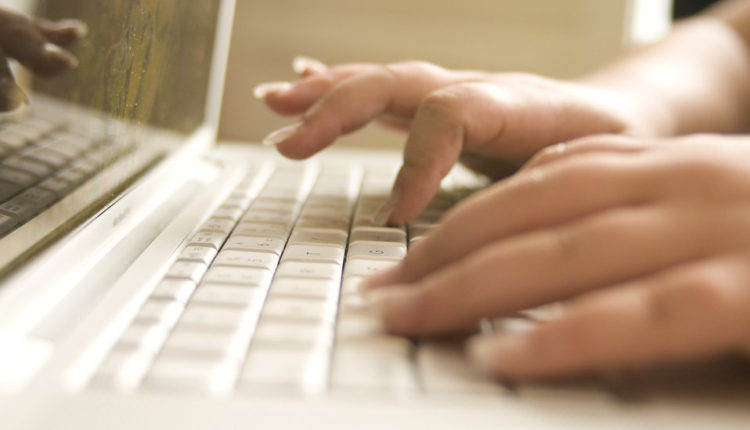 Female hands typing on a laptop keyboard.