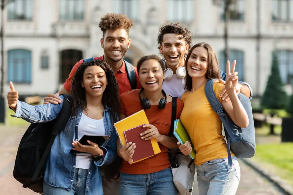 Four young college students smiling and posing together for a cheerful group photo.