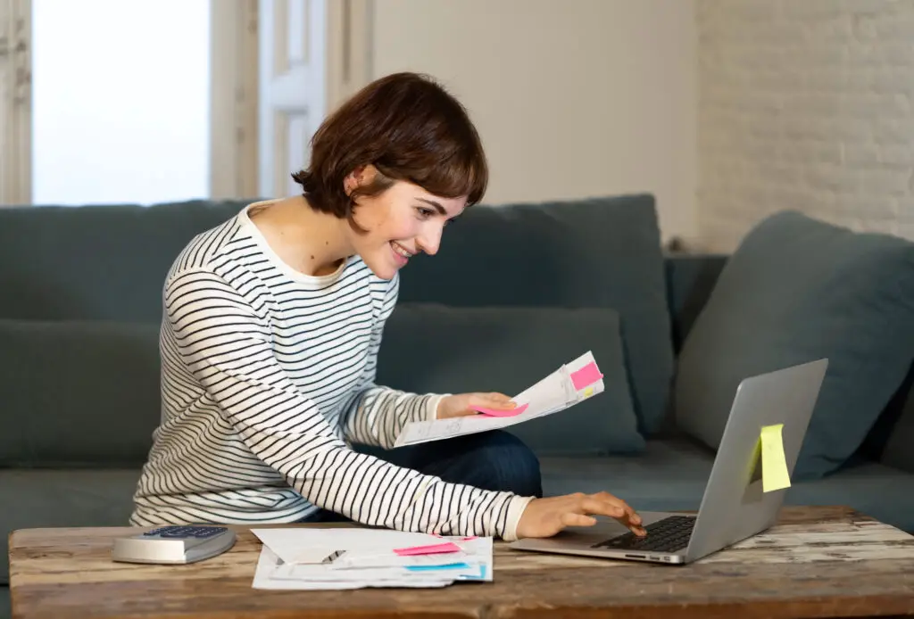 A  female college student sitting on a couch with a laptop