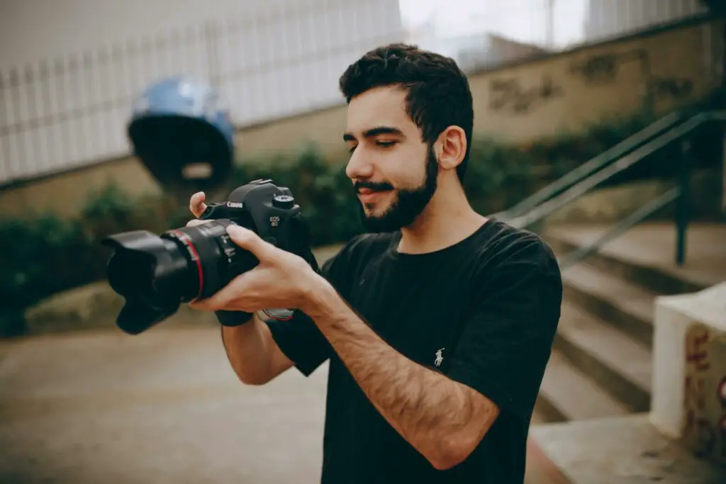 A college student standing outside, holding a camera