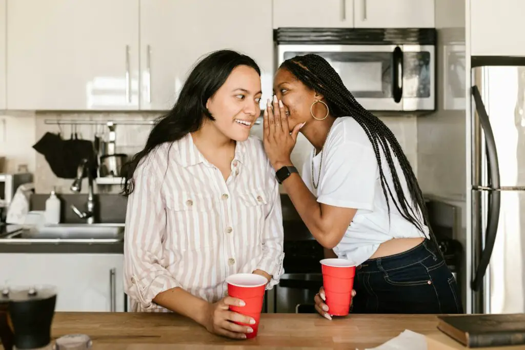 Two women roommates chatting in a kitchen, holding red cups