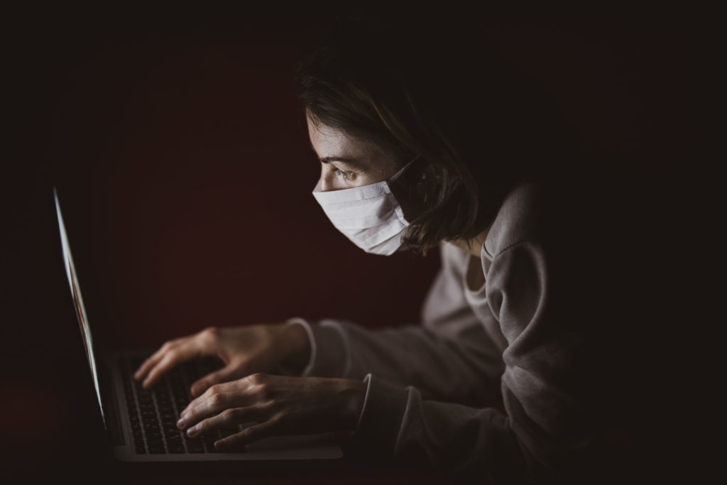 Person with masks in front of laptop