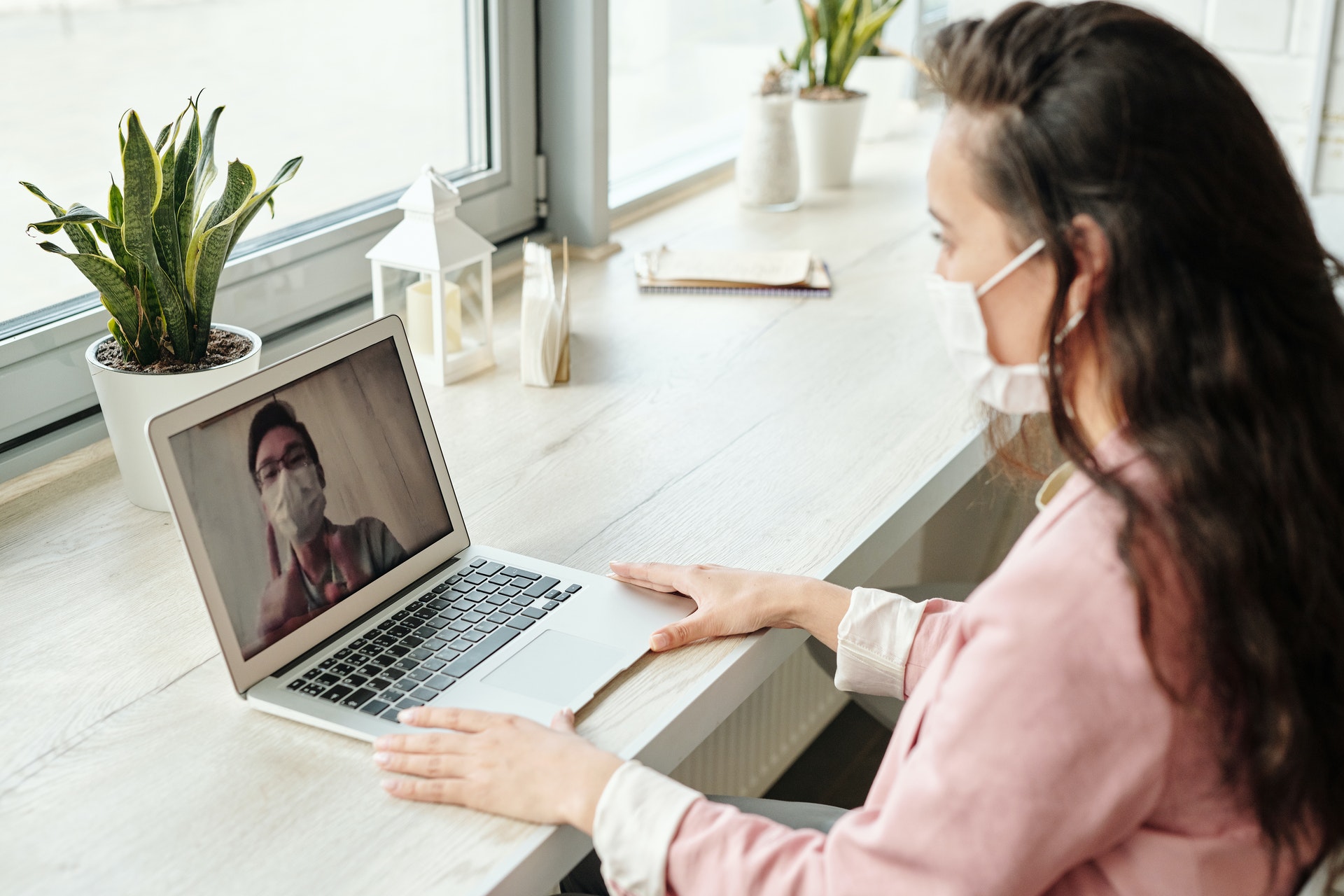 A woman wearing a mask looks at her laptop.