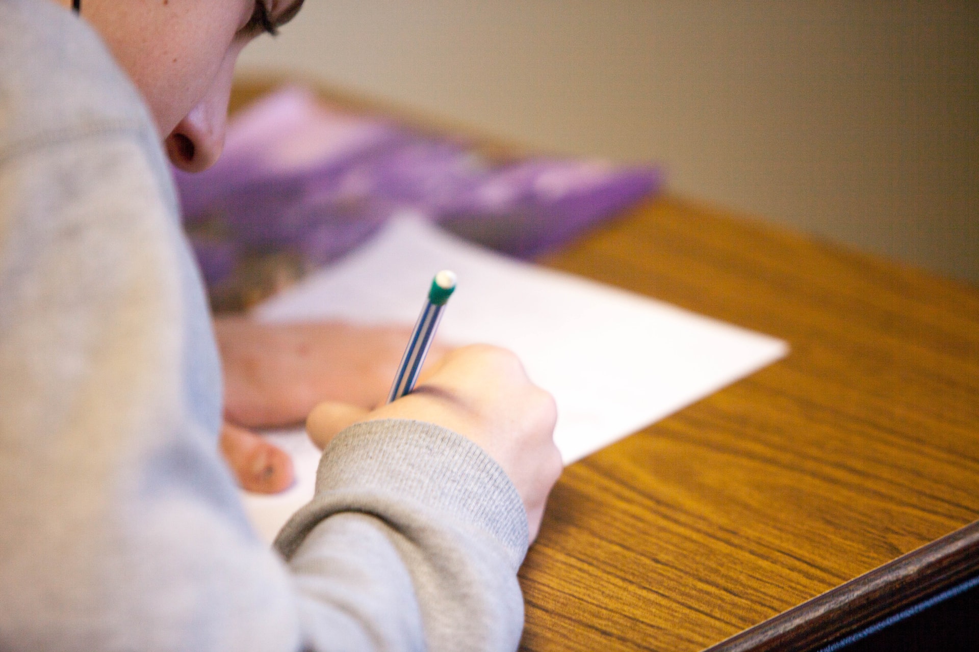 Photo of someone sitting behind a desk making a test.