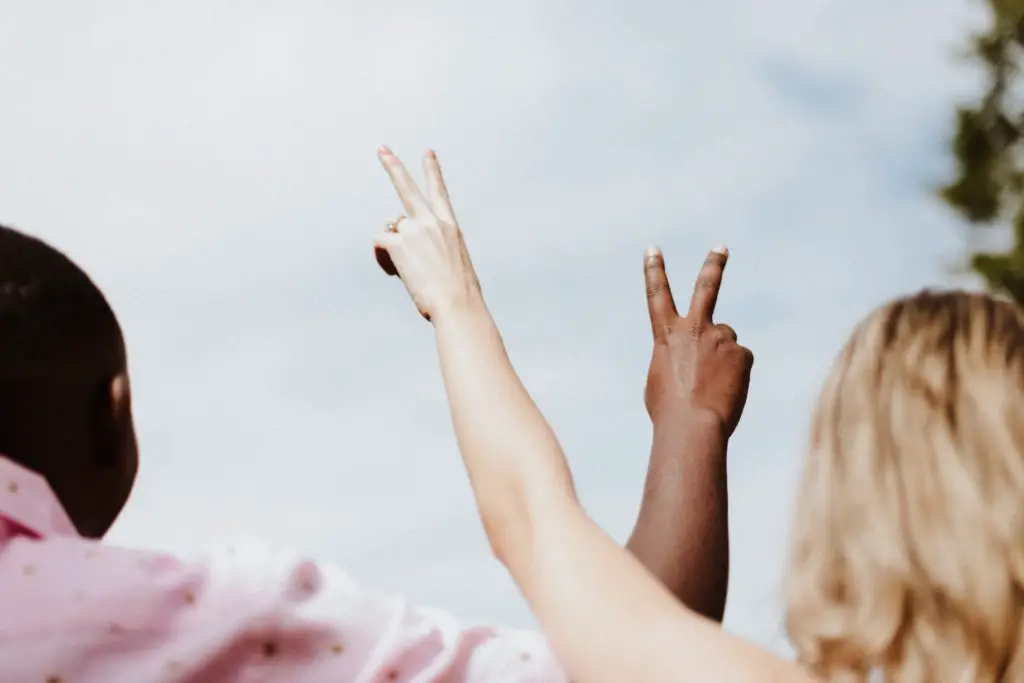 Photo of a Black and a white person making the peace sign