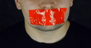 Photo of man with red tape across his mouth