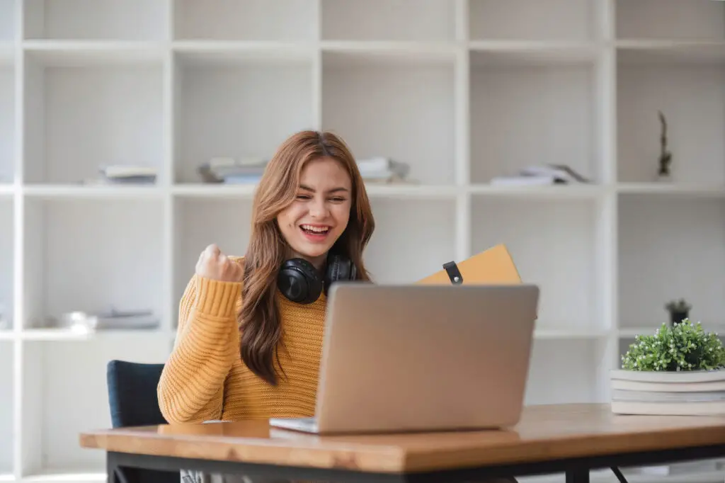 A woman wearing headphones sits at her desk, focused on her laptop, creating a productive remote learning environment