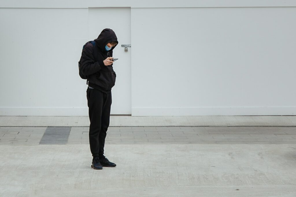 Photo of a student with a mask looking at his phone.