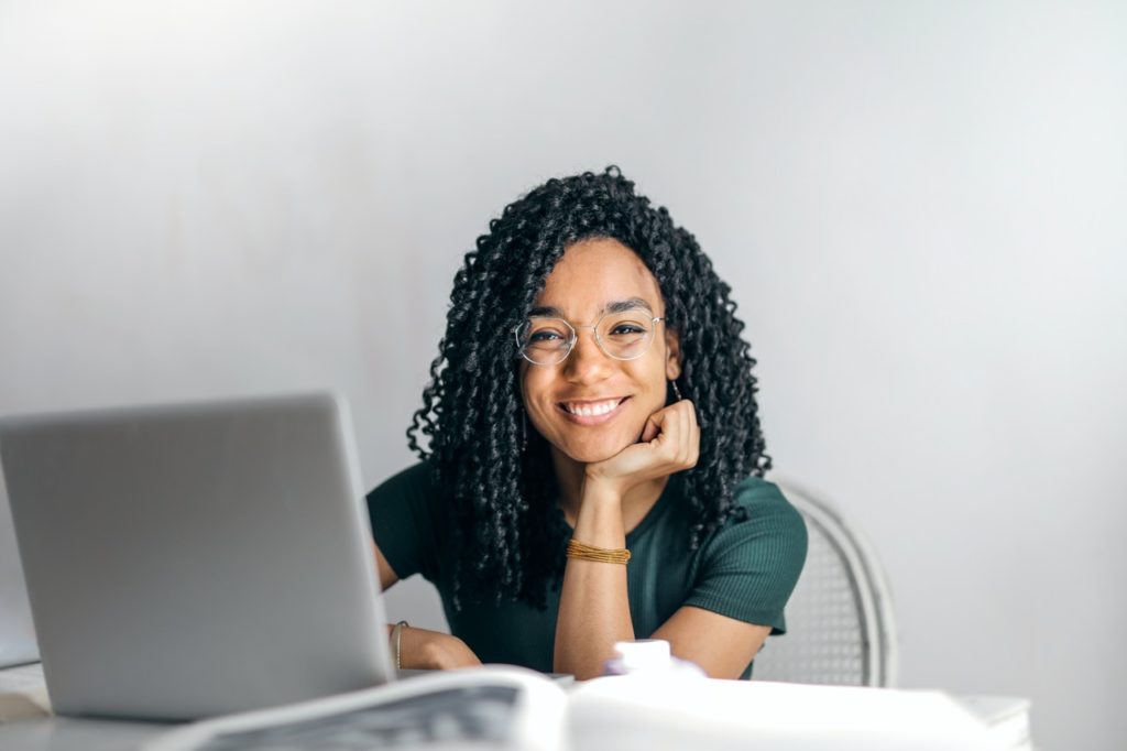 photo-of-college-student-smiling-while-remote-learning-with-computer