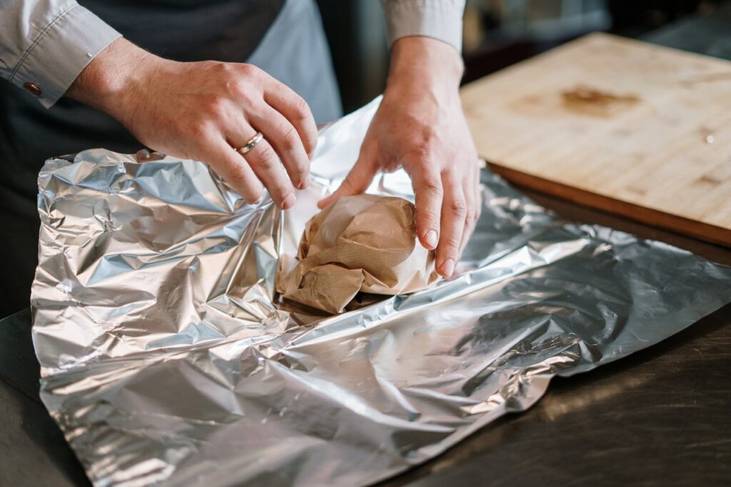 A person packing food in aluminum foil