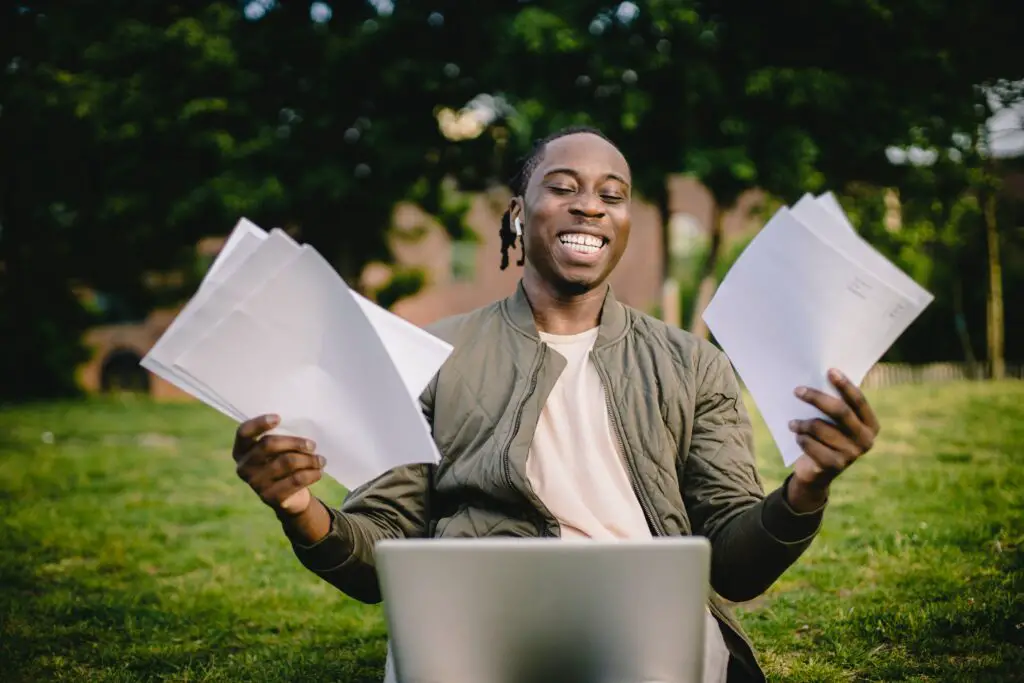 College student is holding papers, happy.