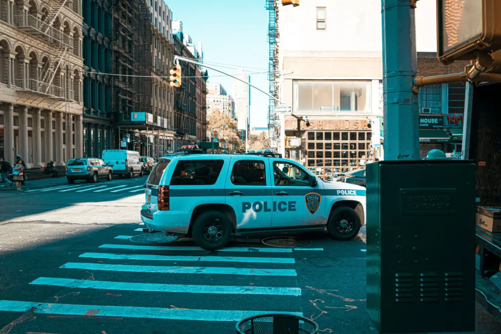 A police car parked haphazardly on top of a pedestrian crossing.