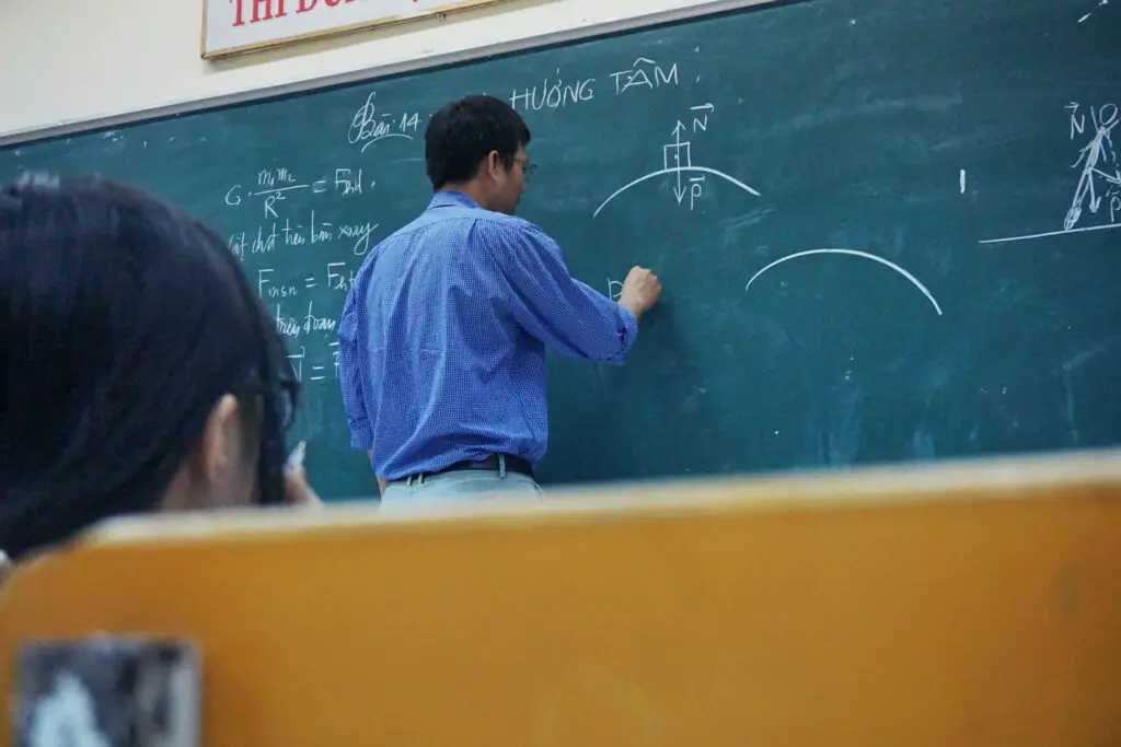 Asian professor drawing mathematical equations on a chalkboard