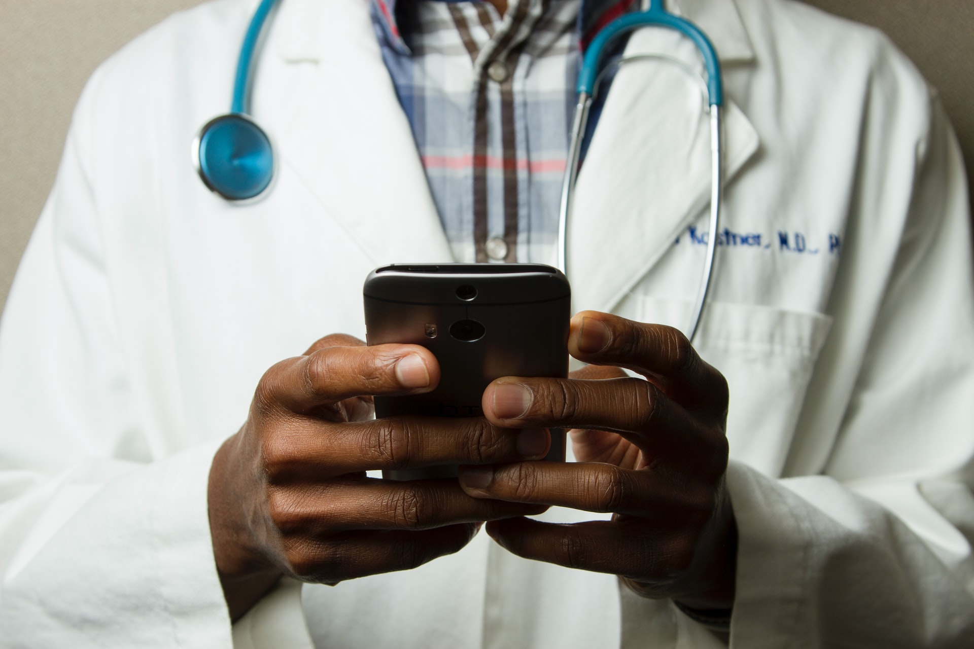 Photo of a Black doctor holding a phone.
