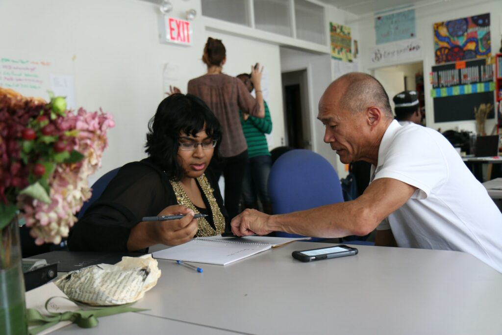 A man pointing at the document that a woman is using