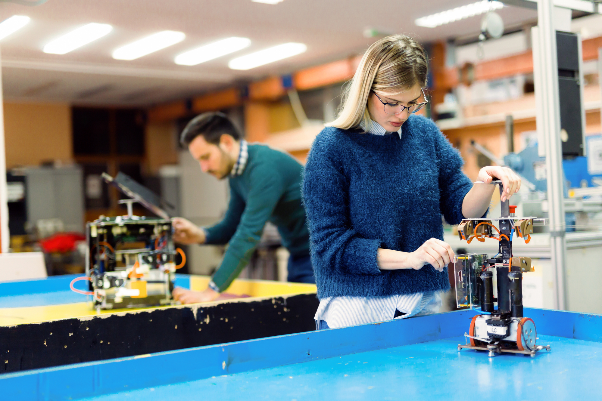 female and male college students working on their robotic projects inside a laboratory
