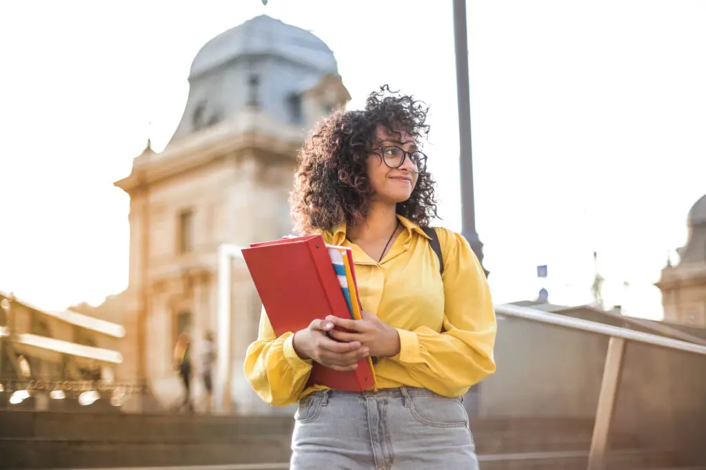 A college career counselor with glasses and a yellow shirt standing on steps.