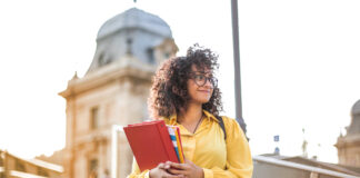 A college career counselor with glasses and a yellow shirt standing on steps.