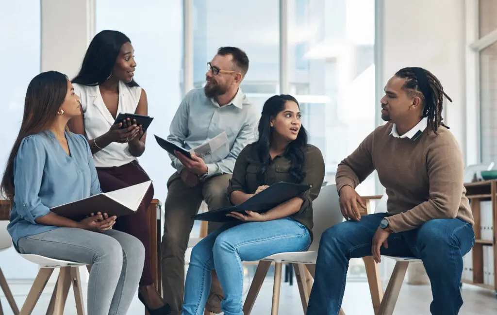 A diverse group engaged in a lively discussion, sitting in a circle, sharing ideas and opinions.