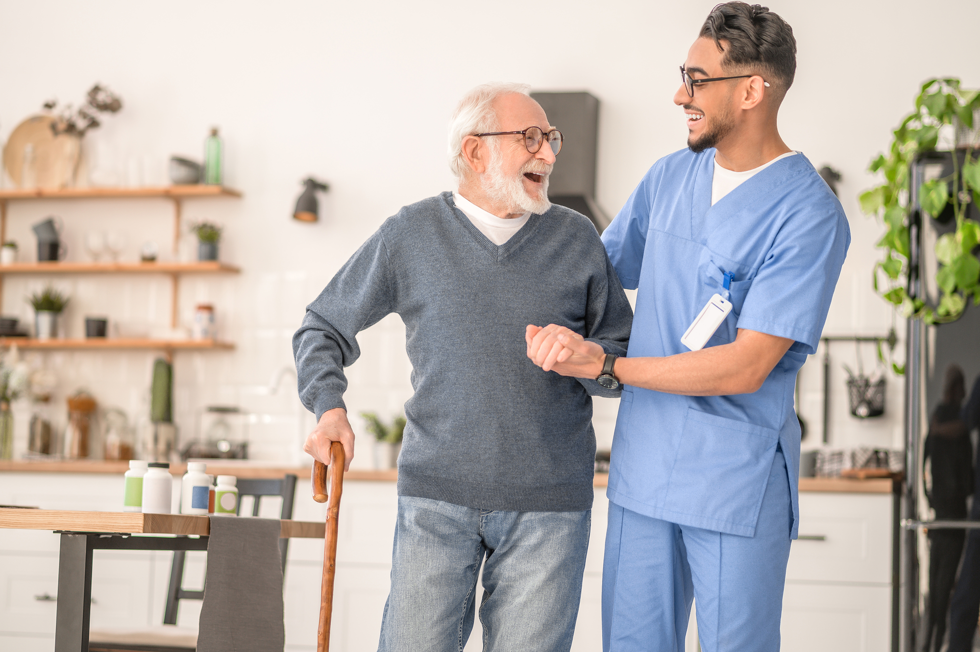 male college student wearing a blue scrub suit guiding a senior patient while working as an intern in a senior home