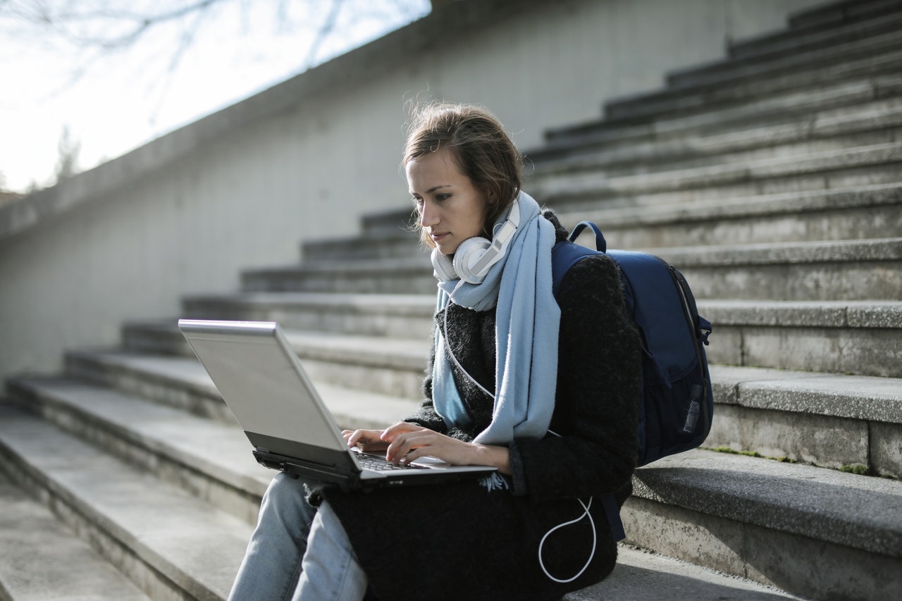 photo-of-girl-researching-a-potential-college-transfer-on-steps-of-university