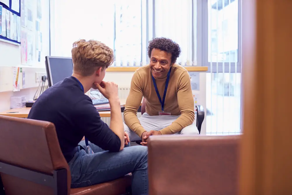 A blond college freshman talks to his campus career counselor to help him choose a college major