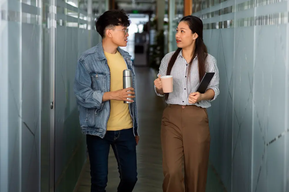 An Asian male informally interviews a female employee working in a company for his summer job to help him decide on a college major