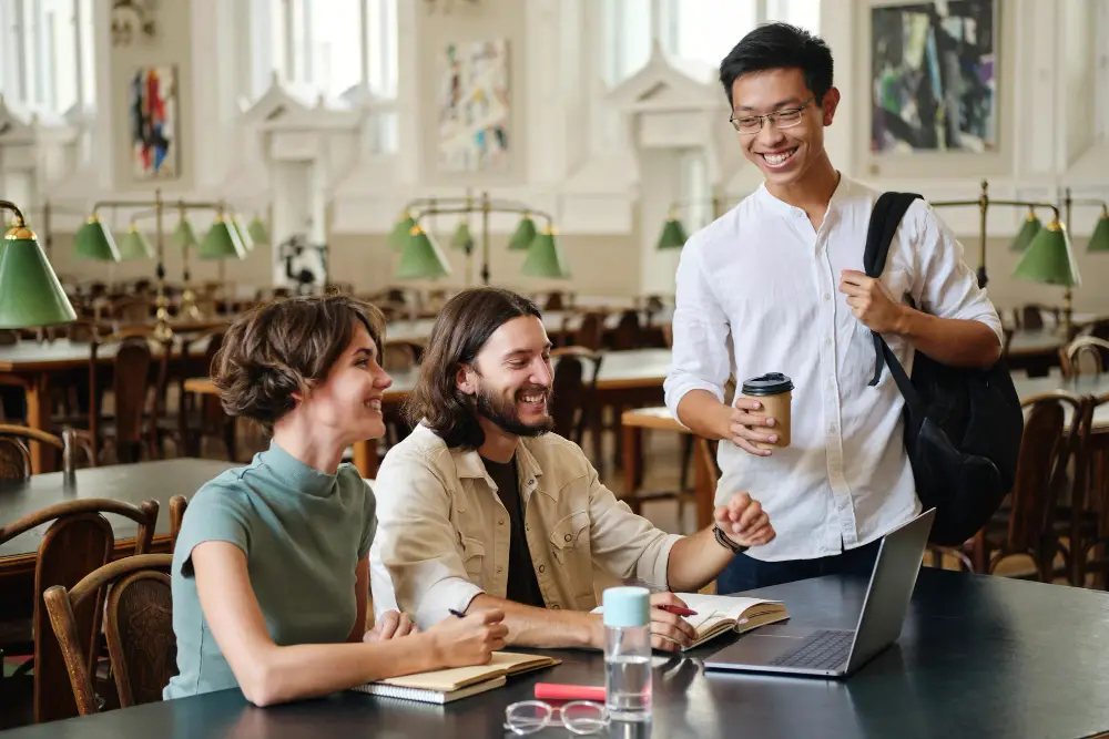 A smiling and standing Asian male college student asks two of his seniors for guidance on how to choose a college major 