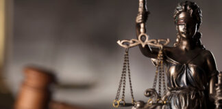 Blind justice statue with judge's hammer in the background