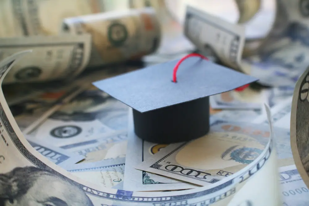 Graduation cap on US dollar bills, student loan debt or scholarschip concept
