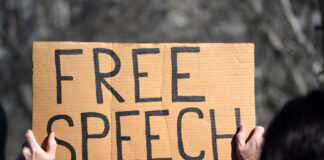 Person holding up sign saying "Free Speech"