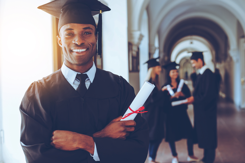 Happy African man in graduation gowns holdin