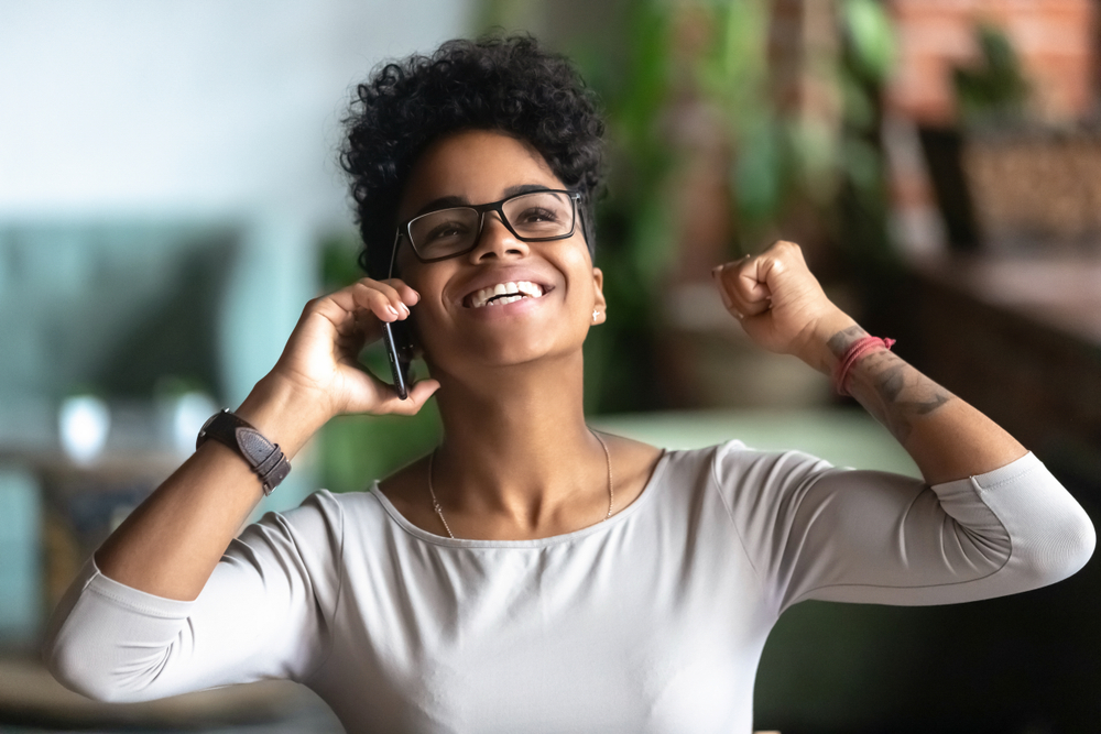 Excited black student talking on mobile phone