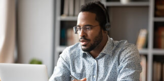 Focused young African studing with headphones during online study class