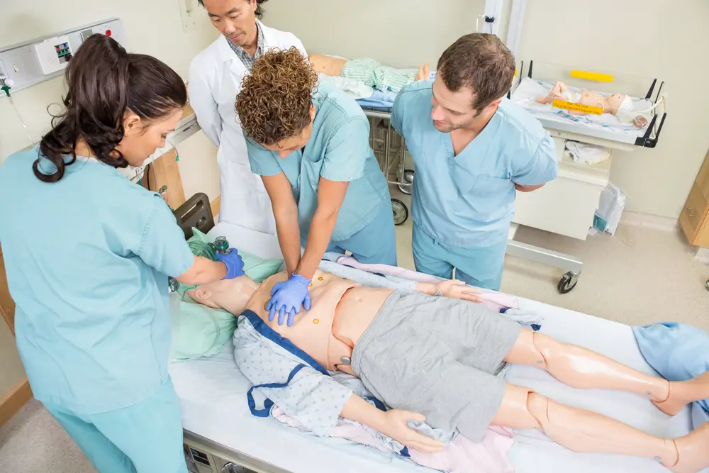 High angle view of nurses performing CRP on dummy patient while doctor standing by in hospital room