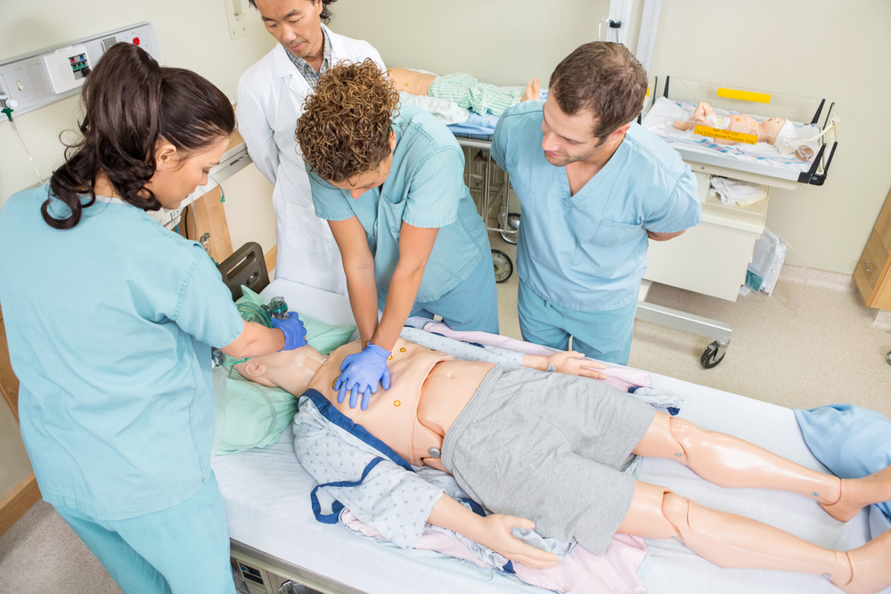 High angle view of nurses performing CRP on dummy patient while doctor standing by in hospital room