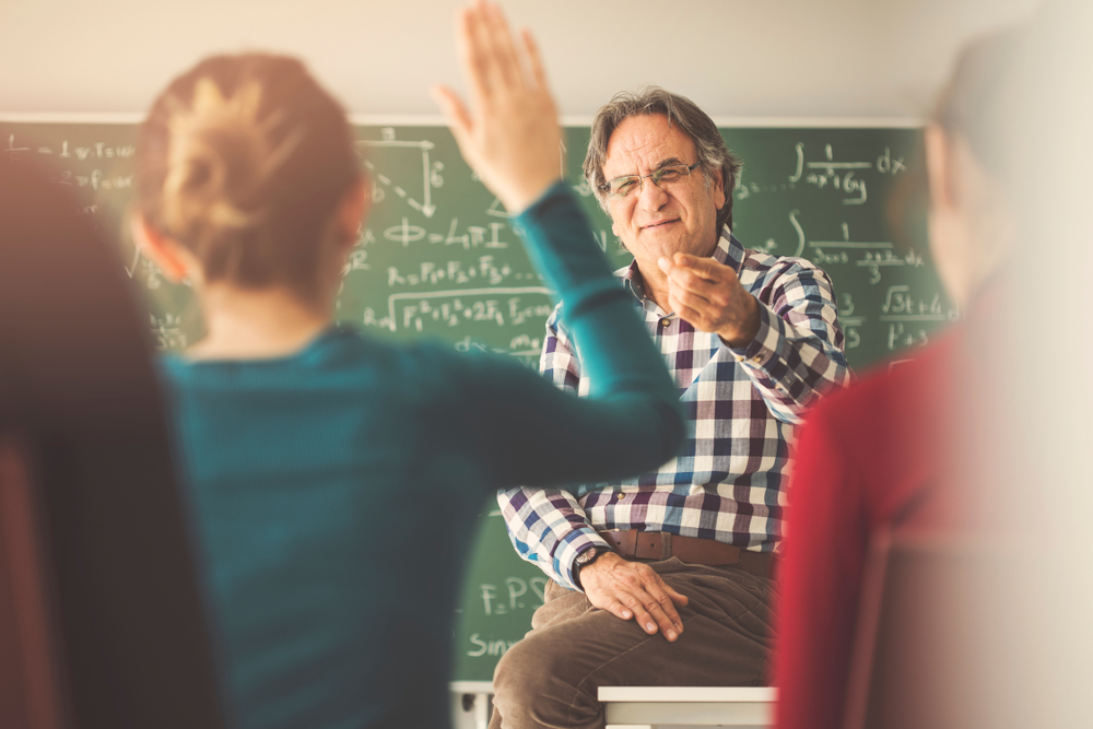 Teacher in the classroom with hands up students