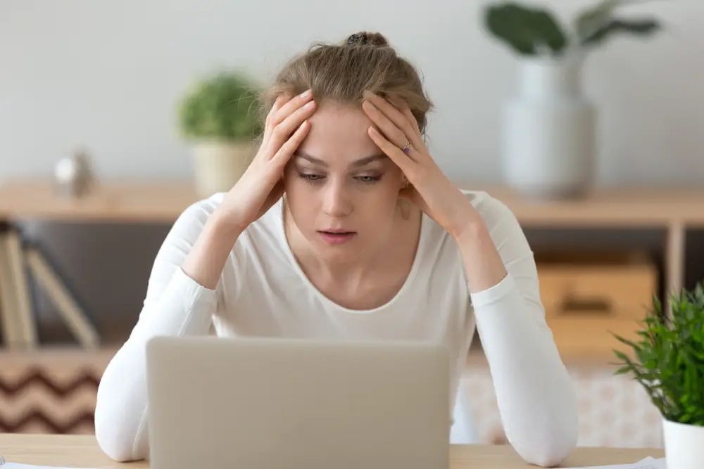 Stressed, frustrated female student looking at laptop, reading email with bad news of failed exam test results.