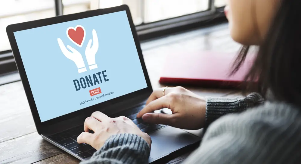 A woman looking at a donation page on her laptop