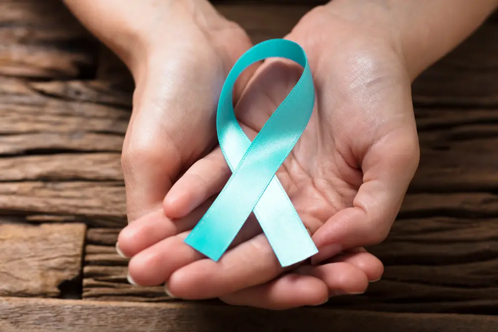 Close up of hands holding a blue ribbon for sexual awareness month