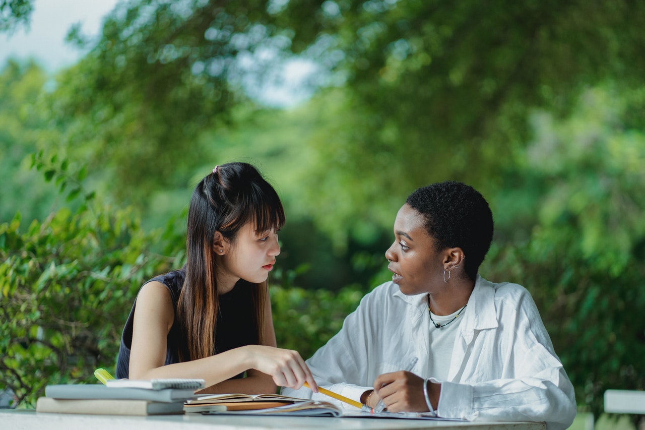 photo-of-two-students-sharing-college-textbook-to-save-money