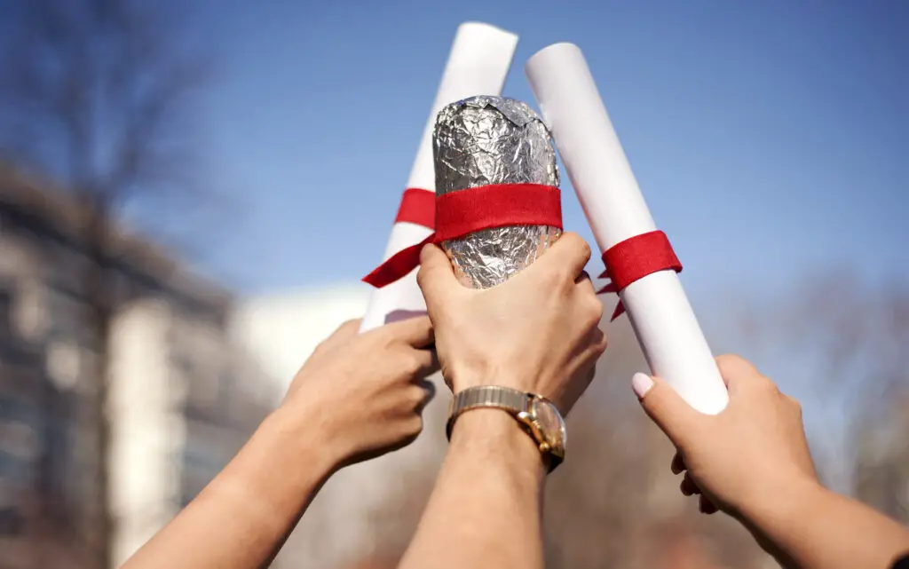 Photo of hands holding up diplomas and a Chipotle burrito
