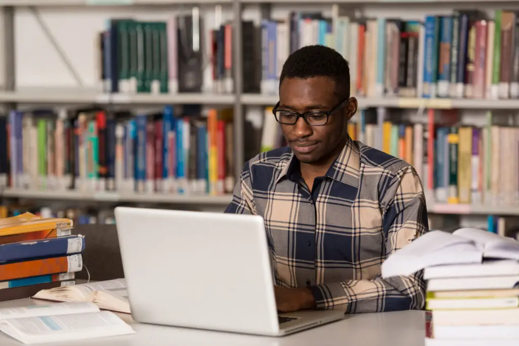 a-male-college-student-reviewing-for-finals-in-the-library-with-laptop