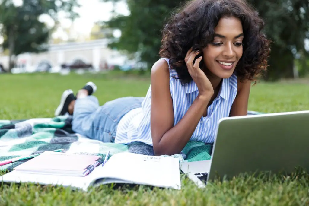 a-female-college-student-reviewing-for-finals-using-laptop-and-books-at-the-park