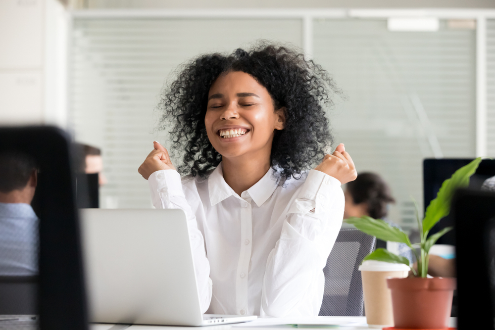 Excited office worker receives good news on her laptop