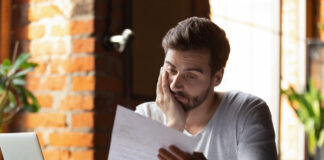 Confused, frustrated young man reading a letter