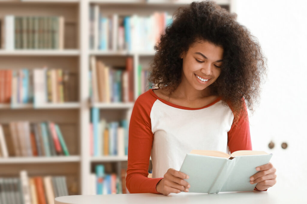 female student reading a book inside a library