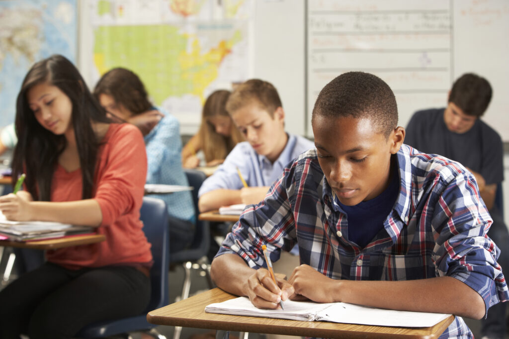 male hand female high school students sitting inside a classroom focusing on reviewing to get high SAT and ACT scores