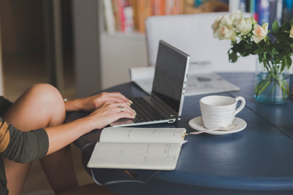 Close-up of a woman's leg with hands on a laptop